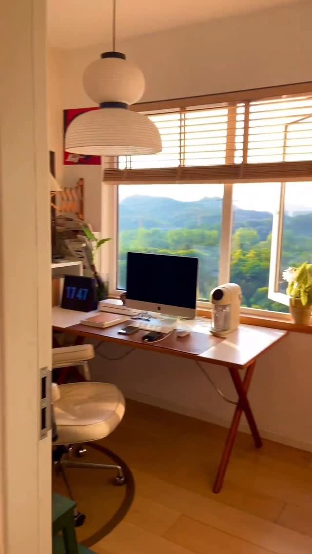 Wooden desk with computer monitor in a small room overlooking green mountains
