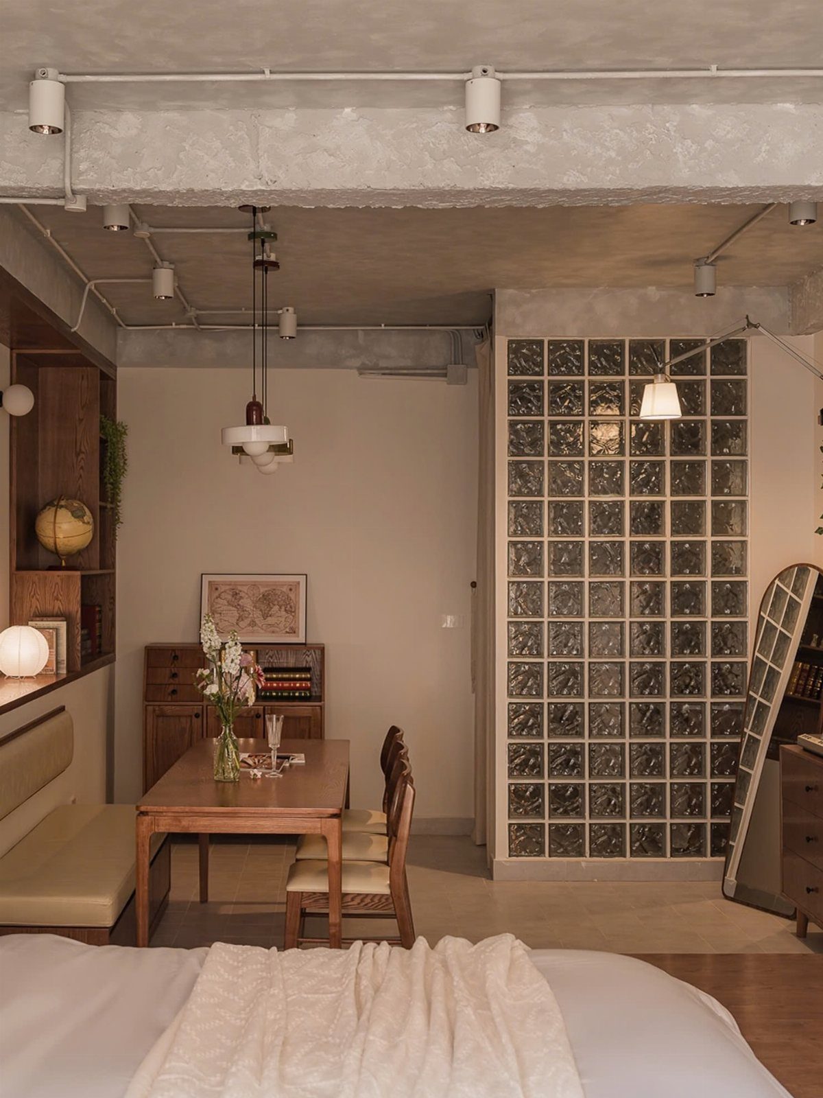 Small studio apartment interior with a dining area and glass block wall partition.