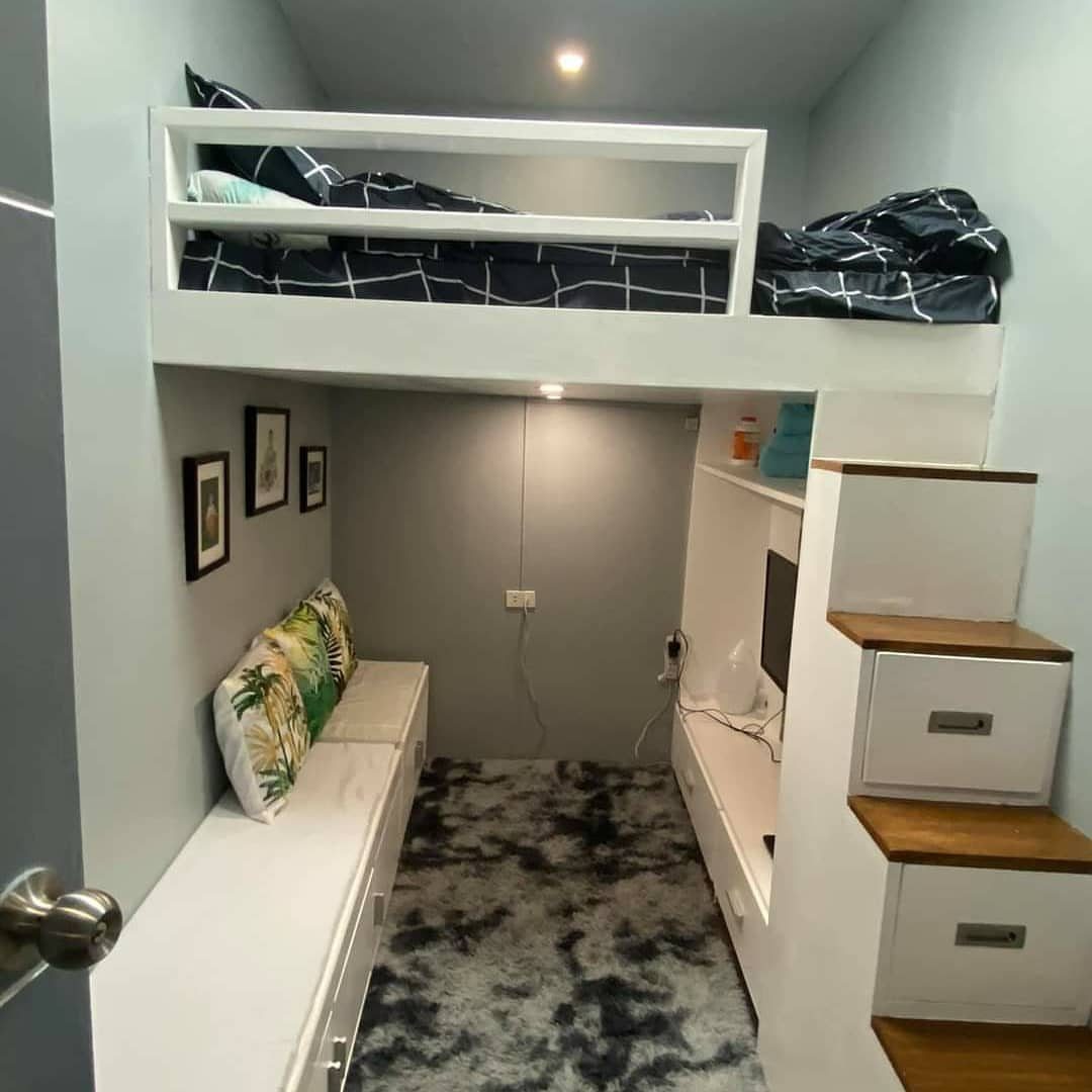 White lofted bed with blue bedding over a built-in sofa and desk area.