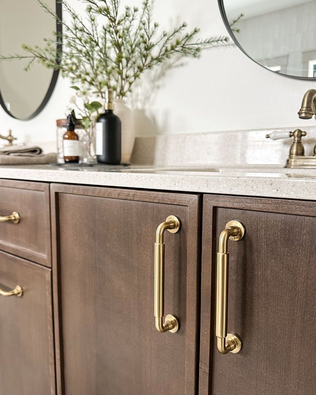 Brown wood bathroom vanity featuring gold metal pulls and knobs on the cabinets.