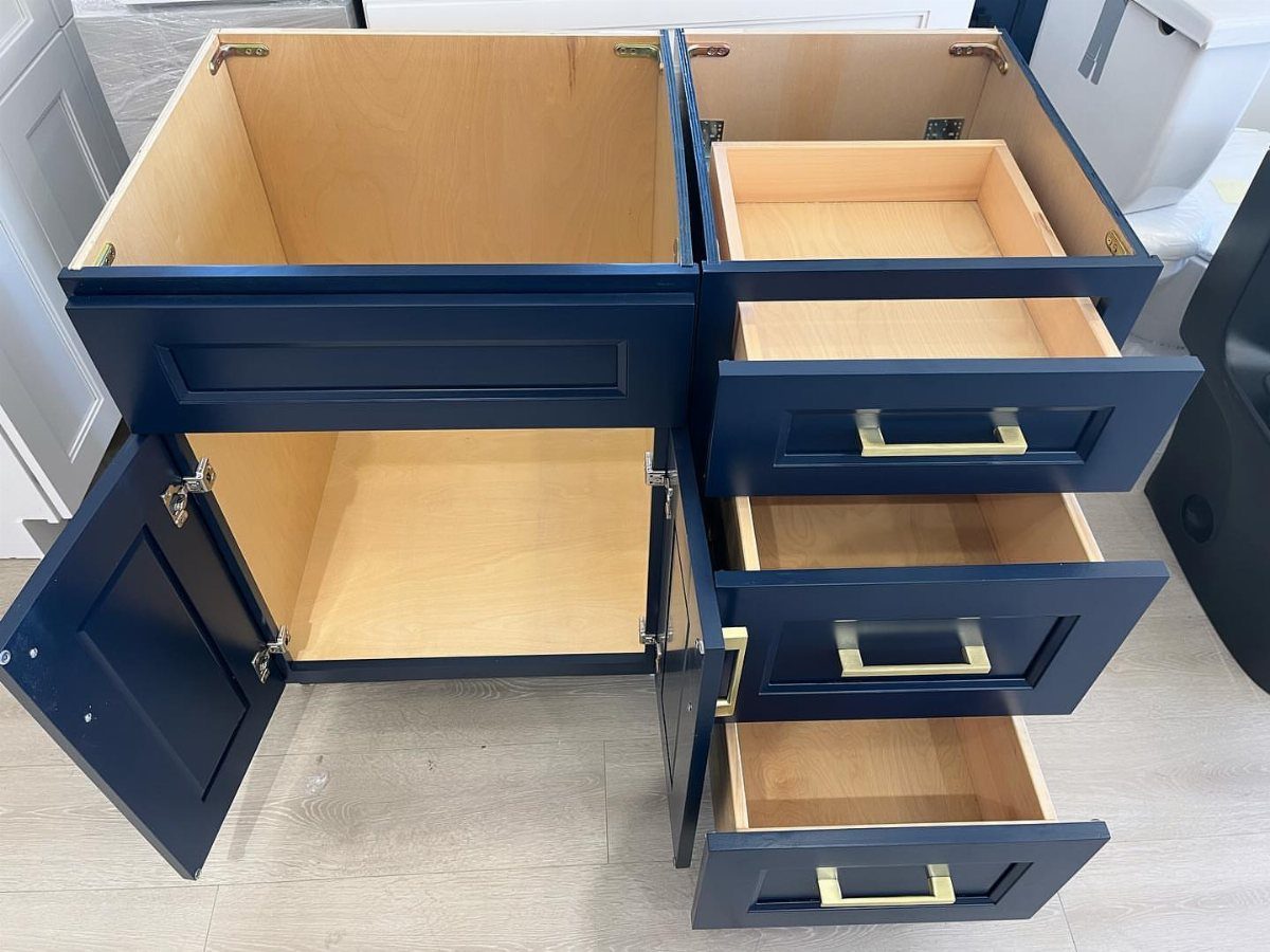 Navy blue bathroom vanity with open drawers and cabinets showing light wood interior.