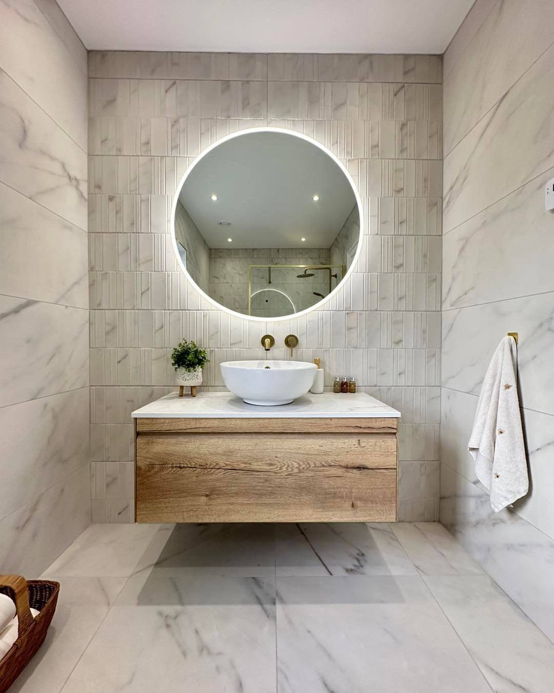Wall-mounted wooden bathroom vanity with white vessel sink and round backlit mirror