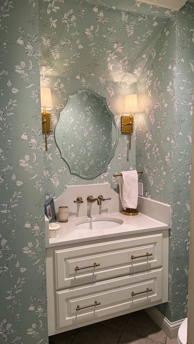 Light green floral wallpaper in a small bathroom with a white vanity and mirror.