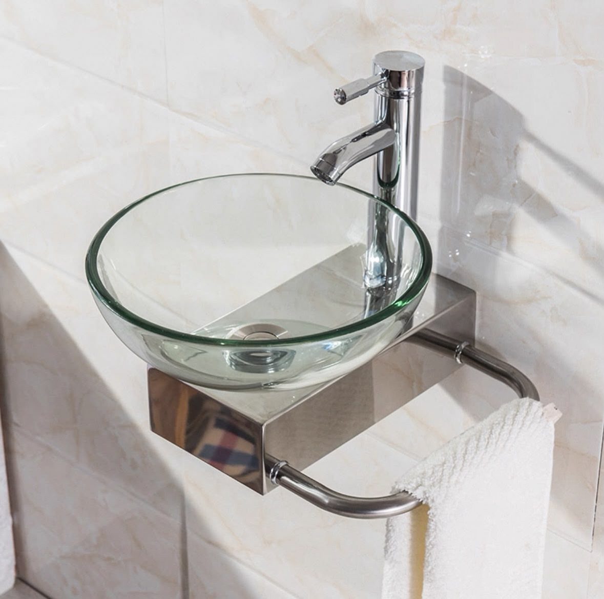 Glass vessel sink on a chrome wall-mounted shelf with a white towel.