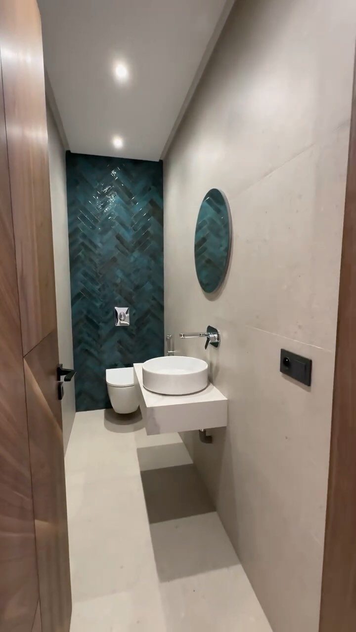 Small bathroom with teal herringbone tile wall, white vessel sink, and neutral tones.