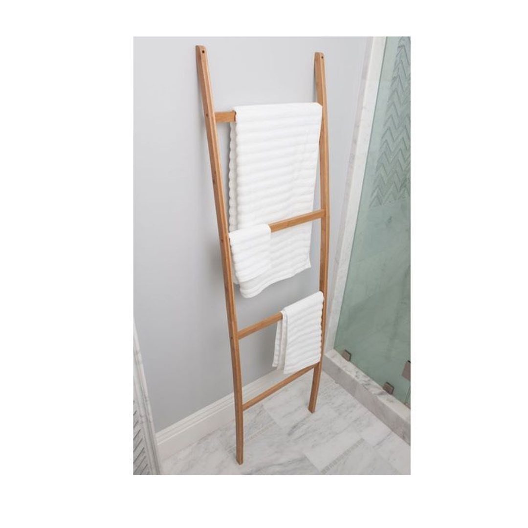 Wooden ladder towel rack with white towels leaning against a grey bathroom wall