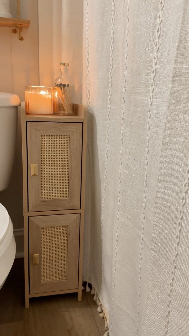 Light wood storage cabinet with rattan doors standing next to a white toilet.