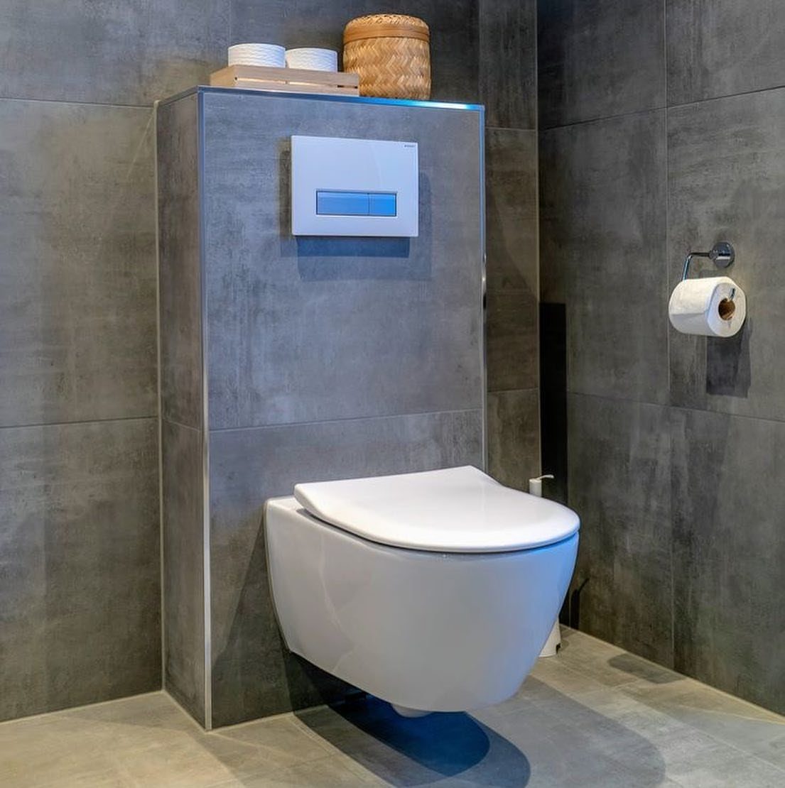 Wall-hung white toilet with concealed tank against grey concrete textured bathroom walls