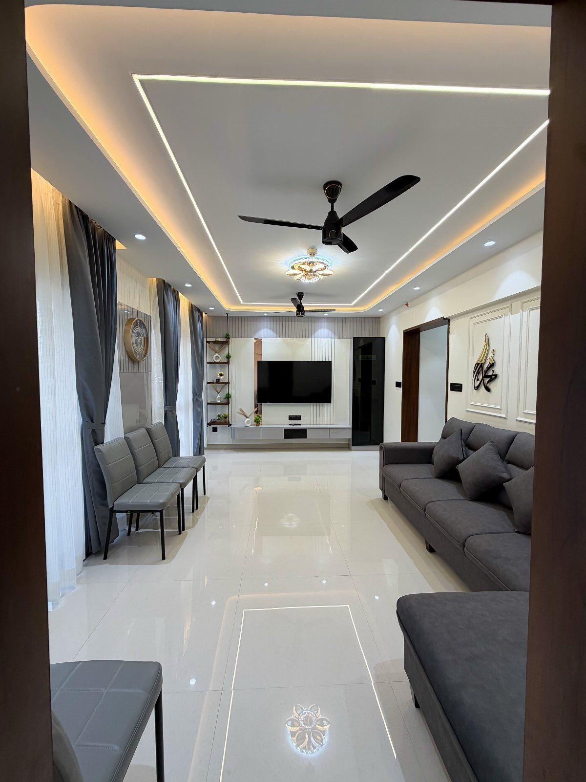 Modern living room with grey furniture, white glossy floors, and recessed ceiling lighting.