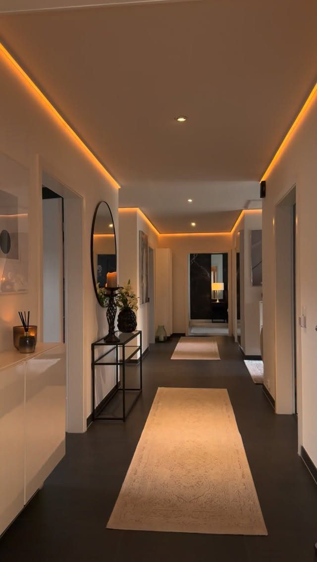 Modern hallway with white walls, warm lighting, and a light-colored runner rug.