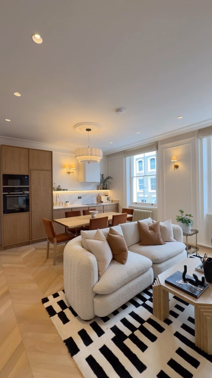 Modern open-concept living room and kitchen with white curved sofa and geometric rug