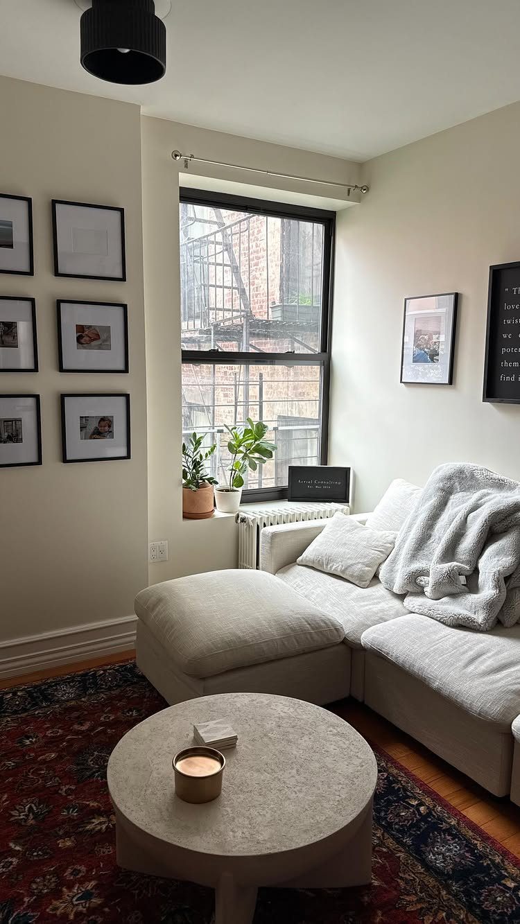 Small living room with white sectional sofa, round coffee table, and gallery wall.