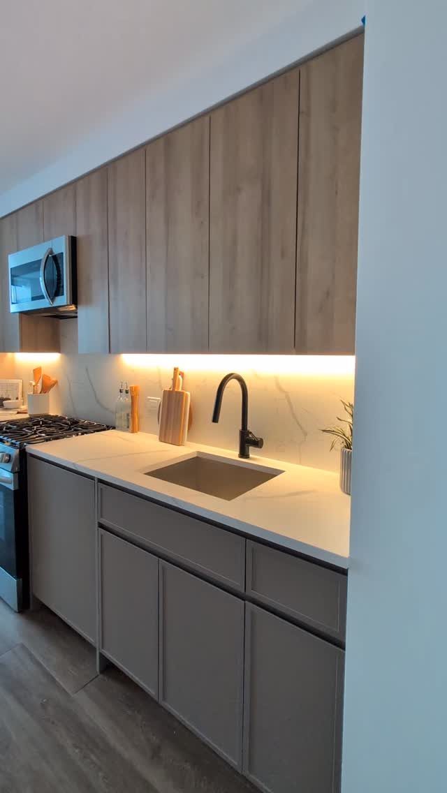 Modern kitchen with light wood upper cabinets and grey lower cabinets.
