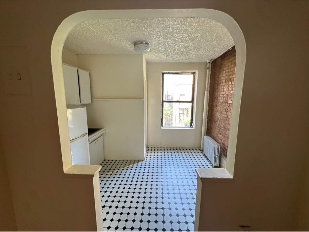 Small kitchen with white cabinets and black and white patterned tile flooring.