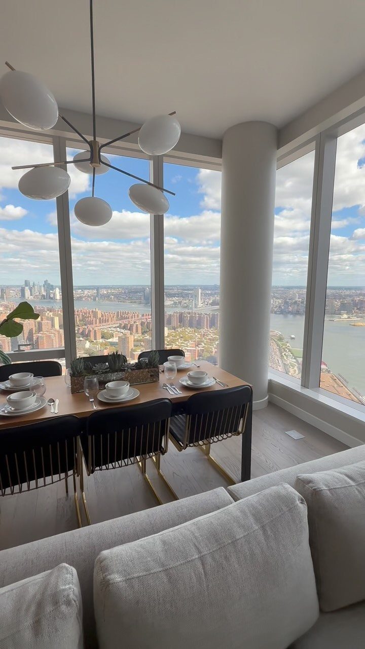 Modern dining area with black chairs and large windows overlooking a city skyline.