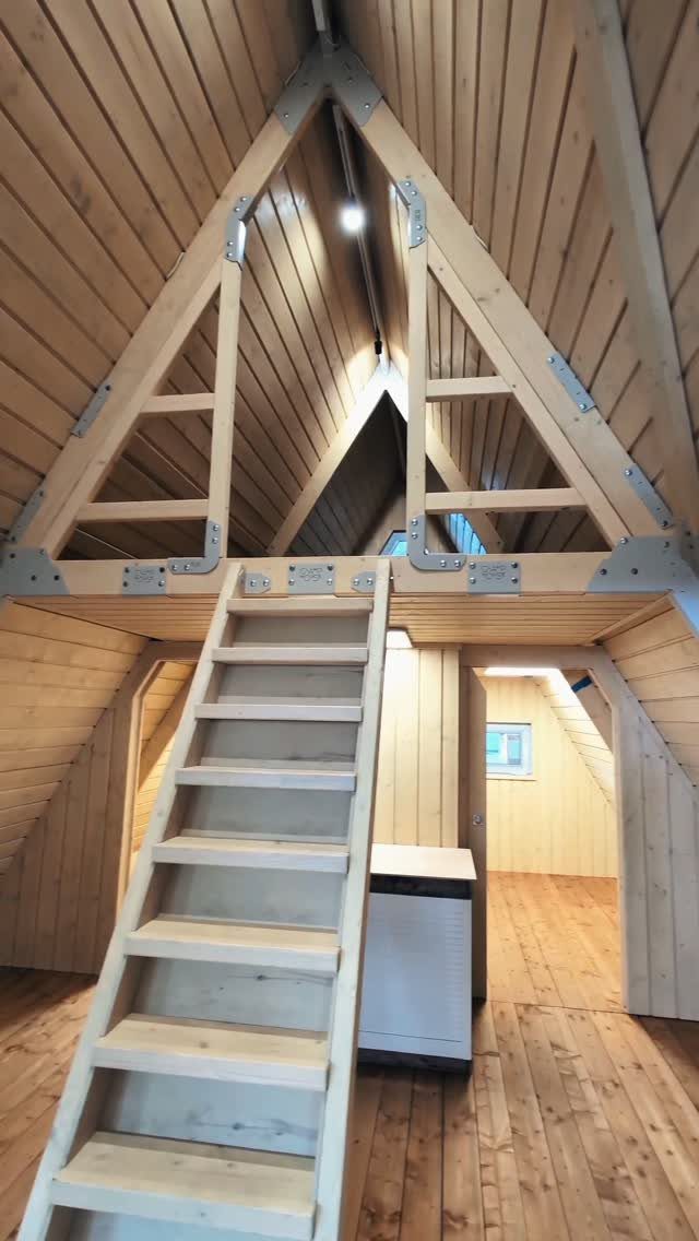 Wooden A-frame cabin interior with a ladder leading up to a loft area.