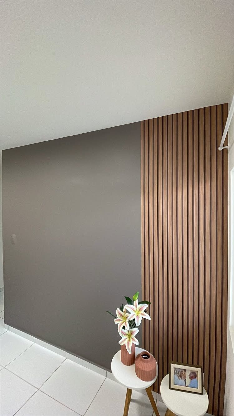 Grey wall with a brown wooden slat accent panel and small white tables.