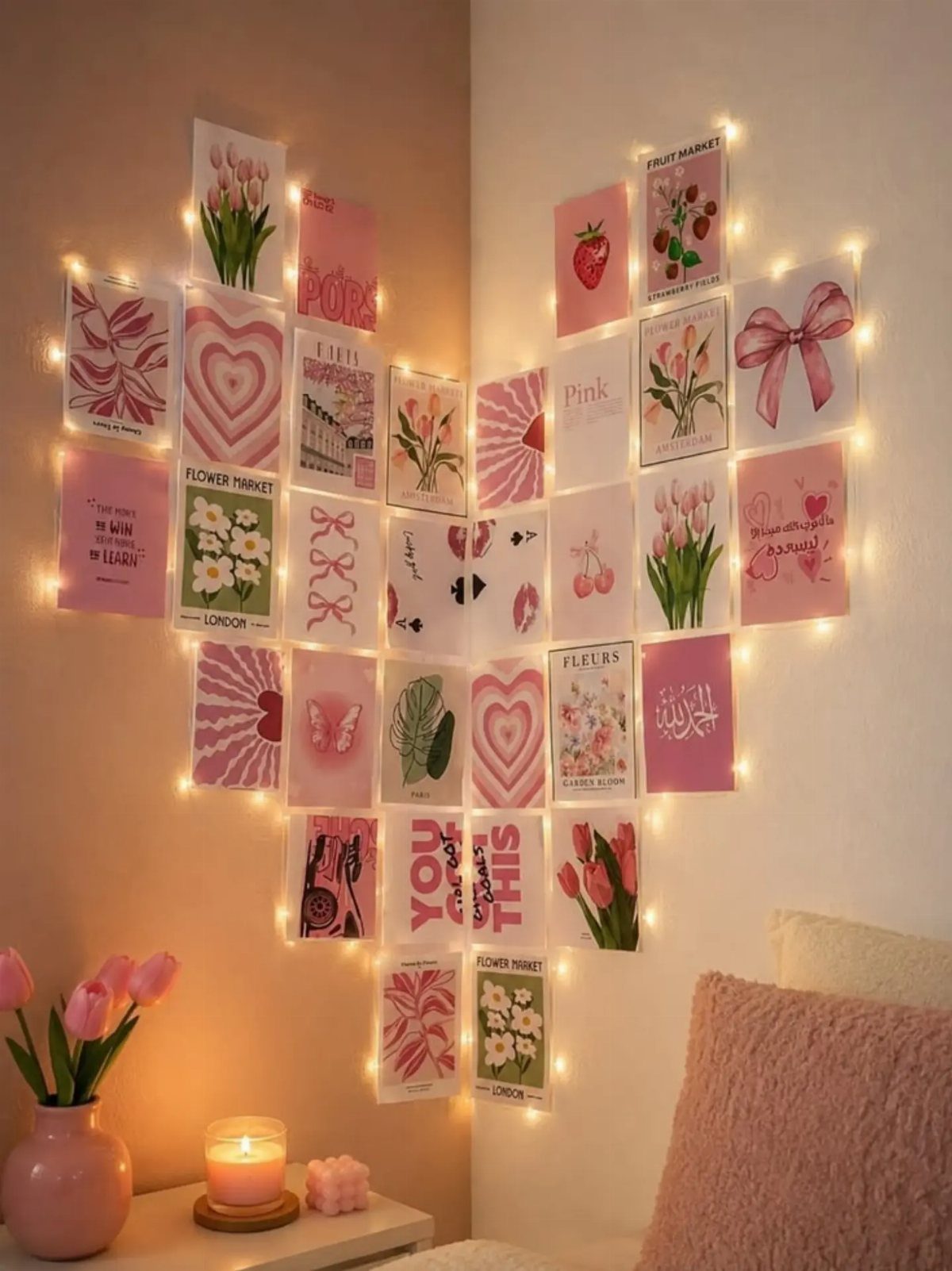 Heart-shaped arrangement of pink aesthetic postcards on a wall with warm string lights.