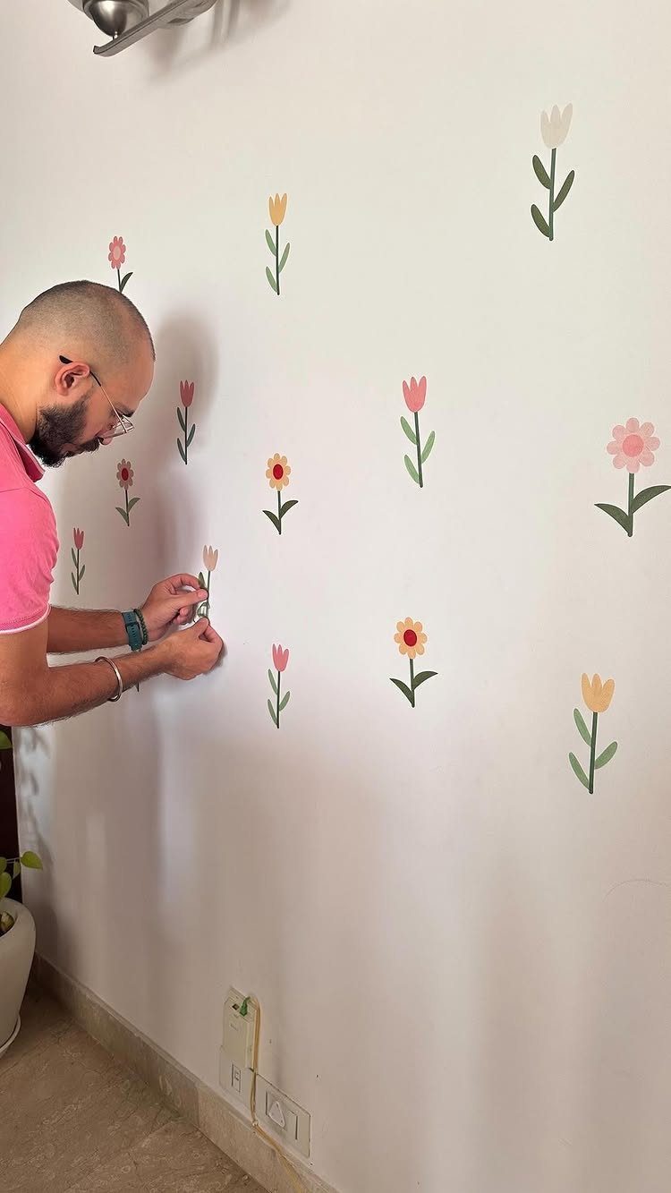 Man applying colorful flower wall decals to a white apartment wall