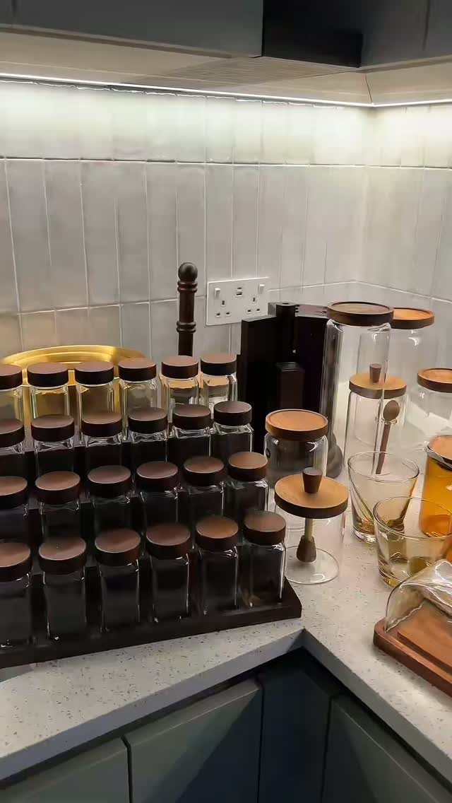 Glass spice jars with wooden lids organized on a white kitchen countertop
