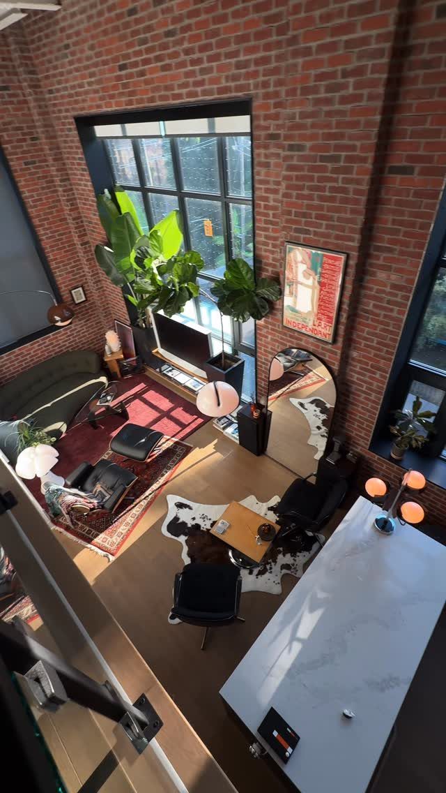 Loft apartment interior with red brick walls and a large window wall.