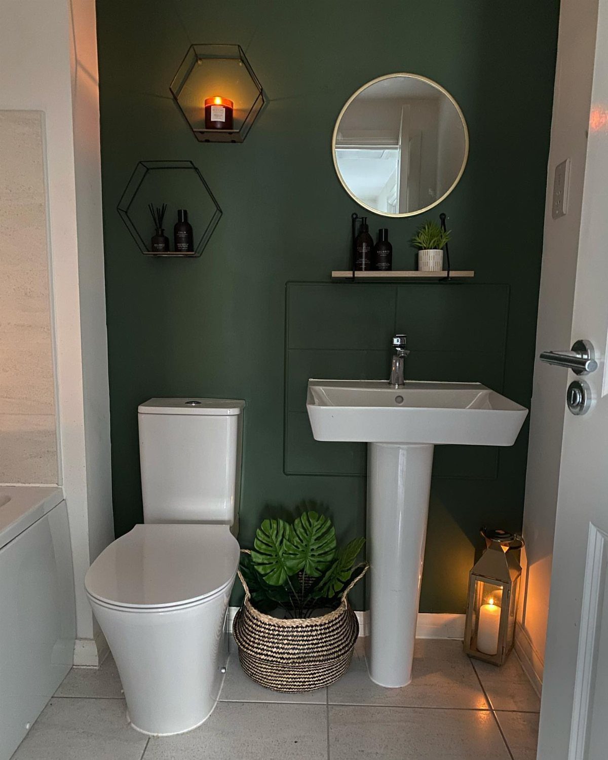 Dark green bathroom walls with a white pedestal sink and white toilet.