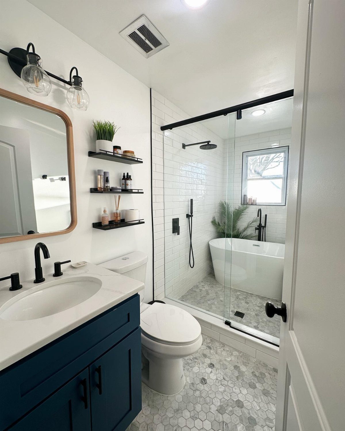 Modern bathroom with blue vanity and a glass-enclosed wet room containing a bathtub.