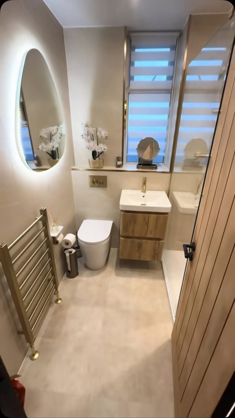 Small modern bathroom with a compact wooden vanity, white toilet, and oval mirror.