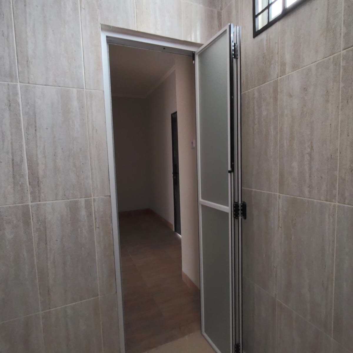 White folding door with frosted glass panels opening into a light-colored hallway.