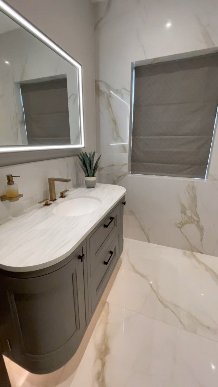 White marble large tiles on walls and floor of a modern small bathroom.