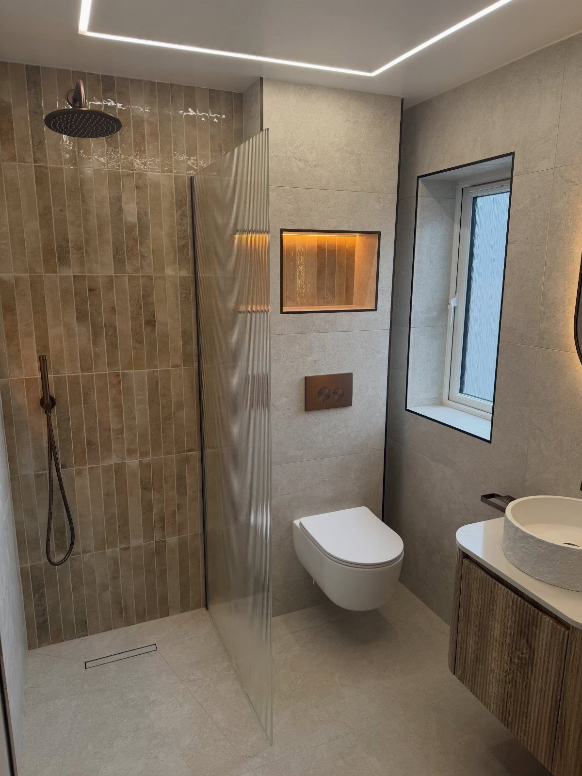 Walk-in shower with glass partition in a modern neutral toned small bathroom