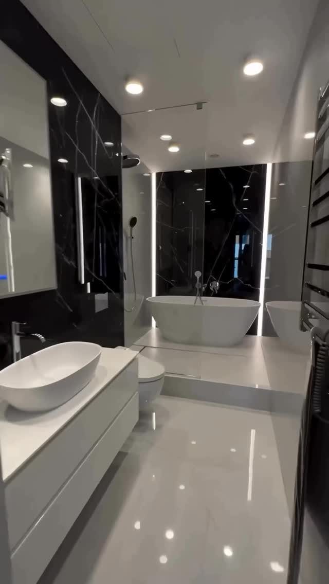 White freestanding bathtub on a platform in a modern black marble bathroom