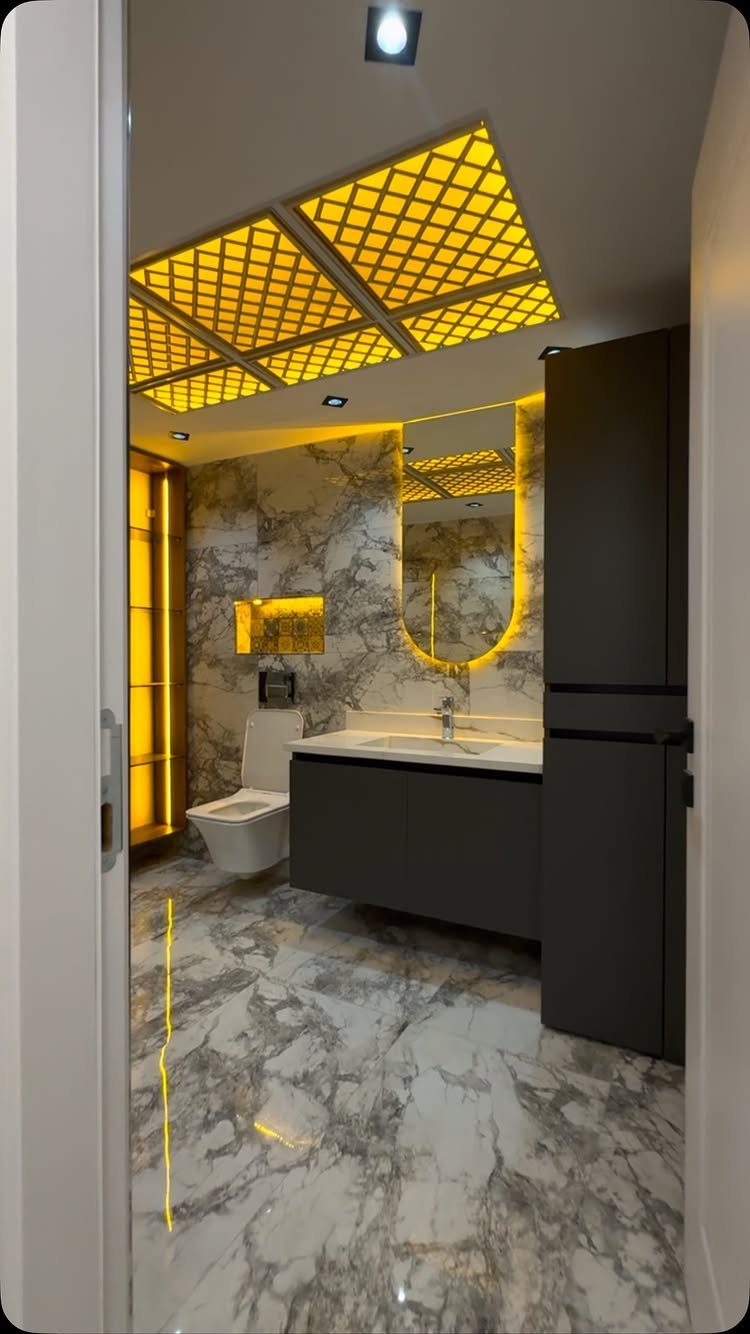 Modern bathroom featuring a glowing yellow lattice sculptural ceiling light and marble surfaces.