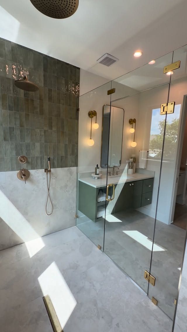 Modern bathroom with dark green tiles, white marble, and gold shower hardware.