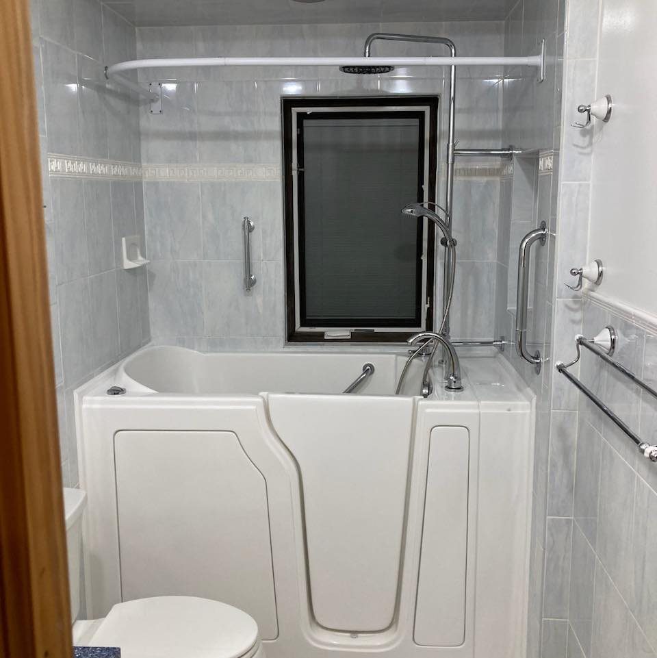 Walk-in bathtub with a side entry door and shower fixtures in tiled bathroom