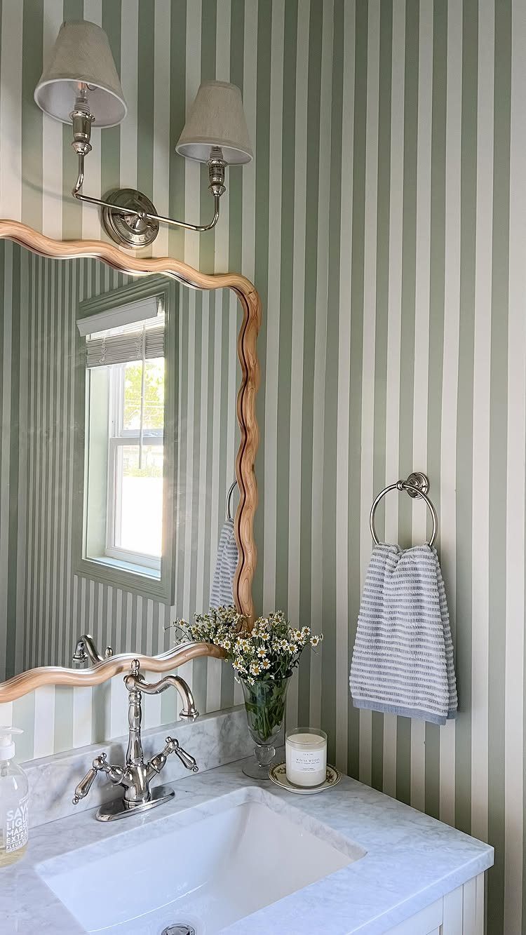 Sage green and cream striped wallpaper in a bathroom with marble vanity.