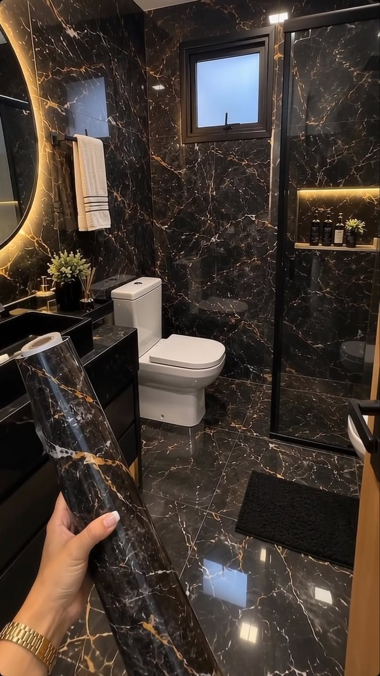 Black and gold marble wallpaper applied to bathroom walls, floor, and a roll