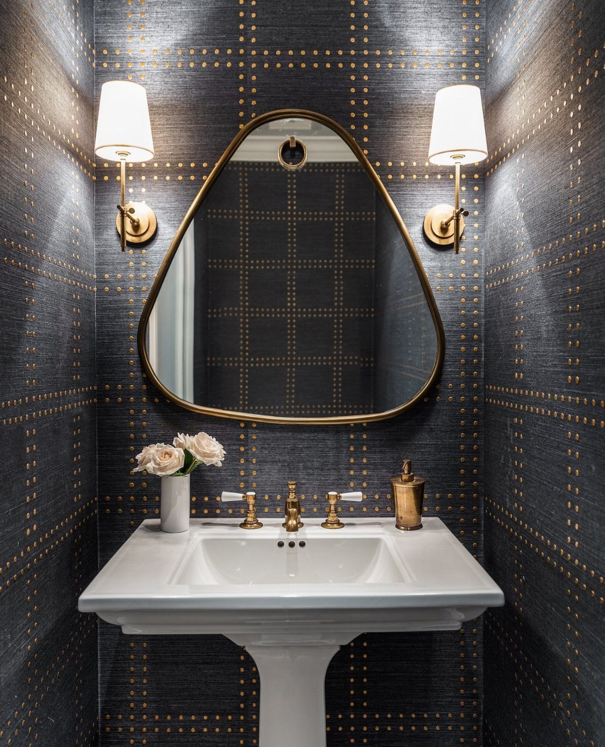 Dark blue wallpaper with gold grid patterns in a bathroom with gold fixtures.