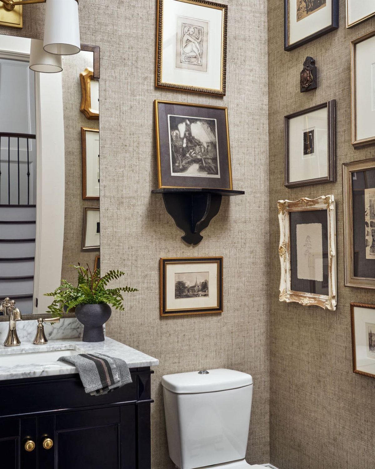 Beige textured wallpaper in a bathroom with a gallery wall and black vanity.