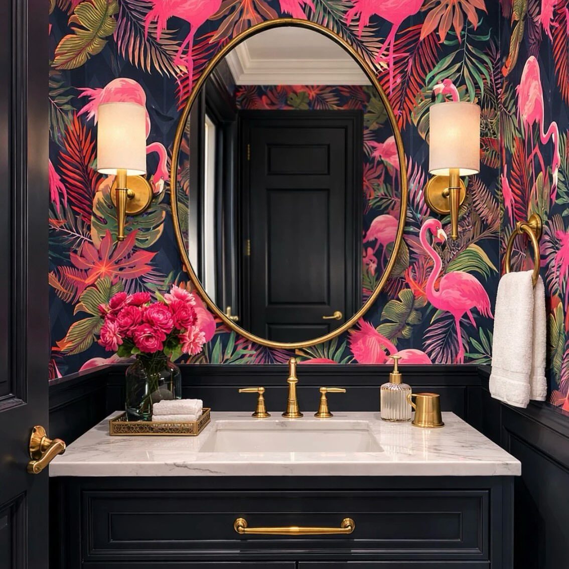 Bathroom vanity with tropical flamingo wallpaper, gold oval mirror, and marble countertop.