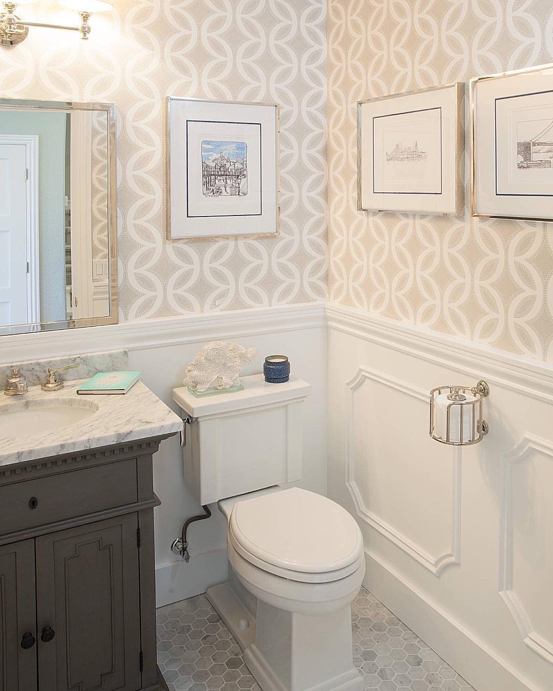 Bathroom with cream interlocking chain pattern wallpaper and white wainscoting panels.
