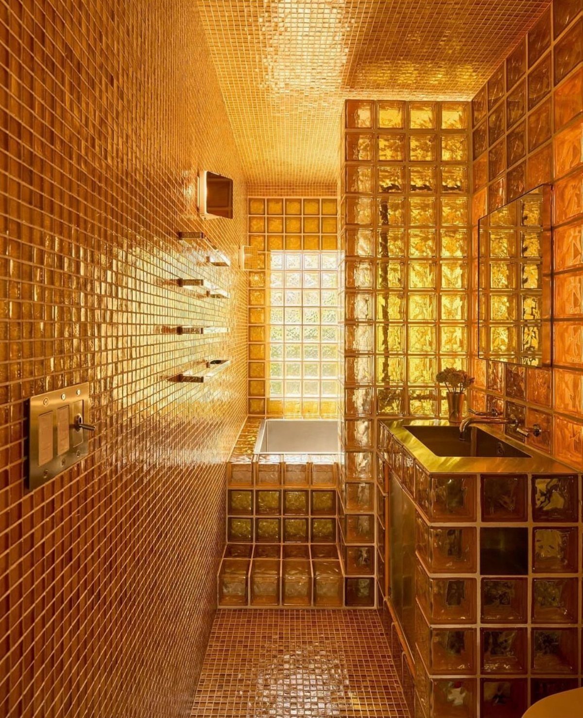 Golden-orange glass mosaic tiles covering the walls, floor, and ceiling of a bathroom
