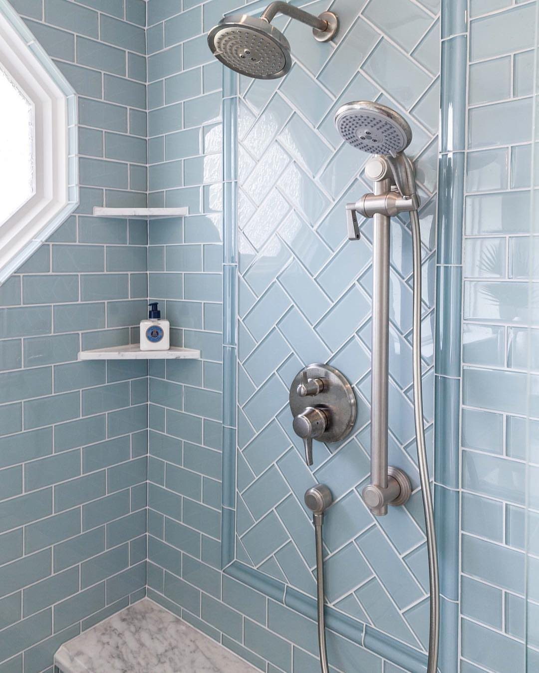 Light blue glass subway tiles in a herringbone pattern on a shower wall.
