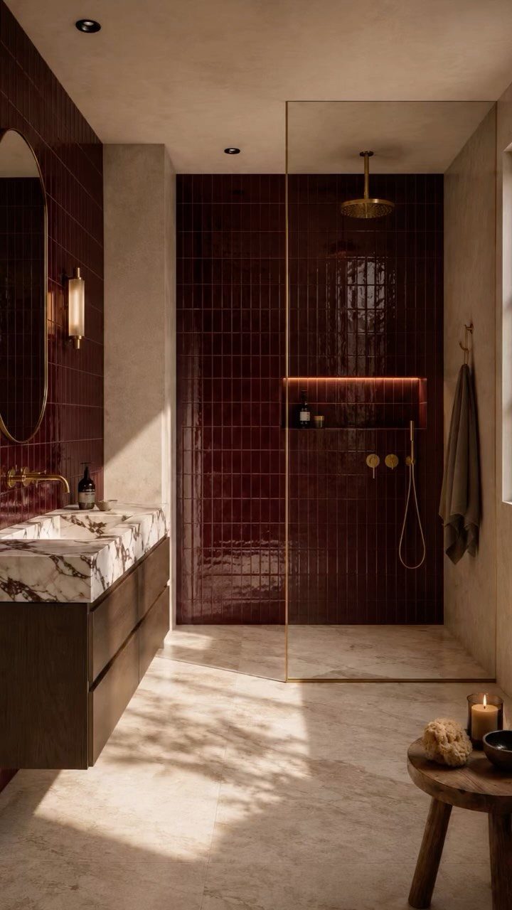 Burgundy glossy glass subway tiles in a modern bathroom with a marble sink.