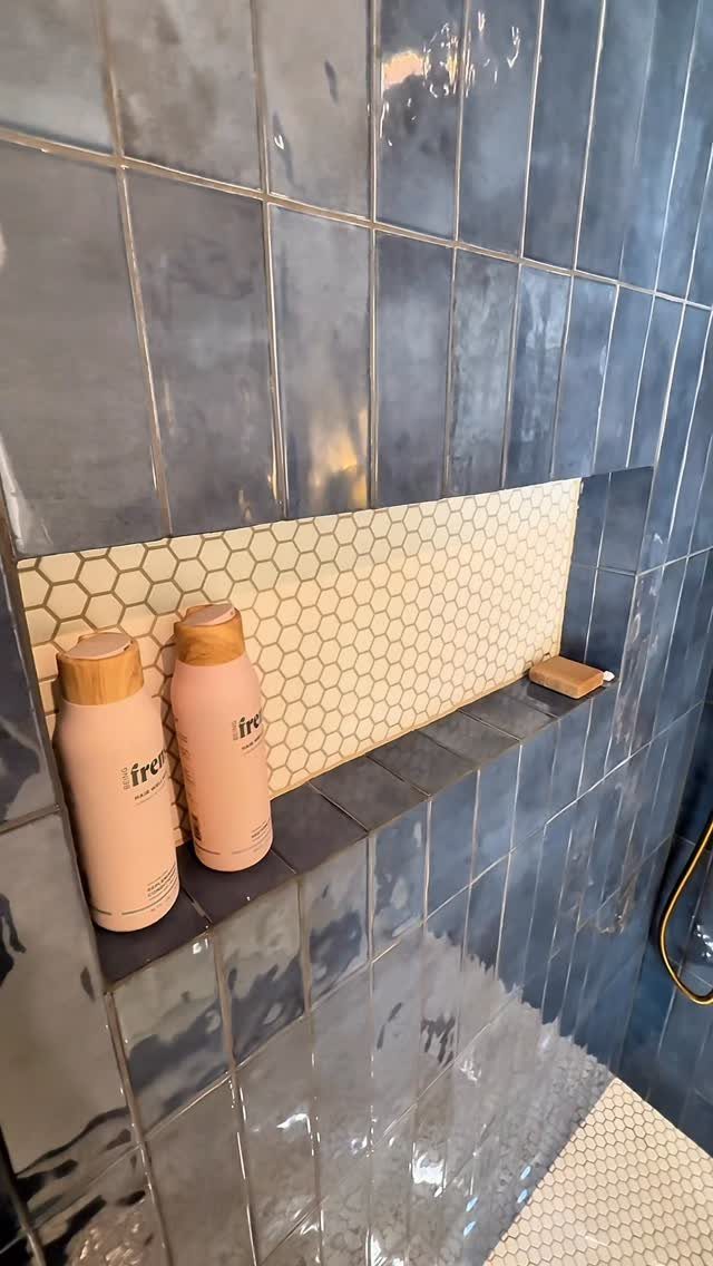 Blue glossy shower tiles with a recessed niche featuring cream hexagonal mosaic tiles.