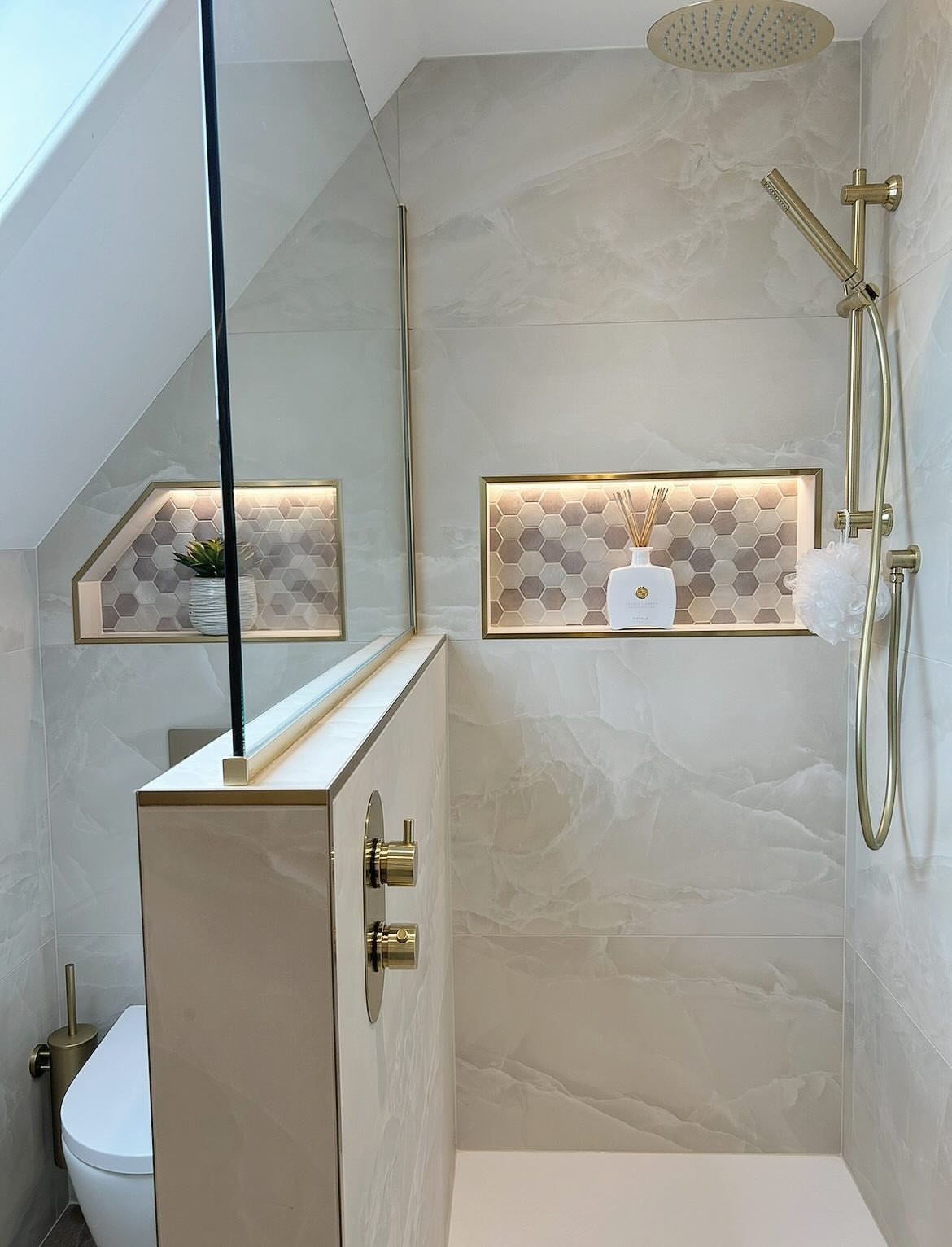 Modern shower with gold fixtures, marble tiles, and a half-glass partition door.
