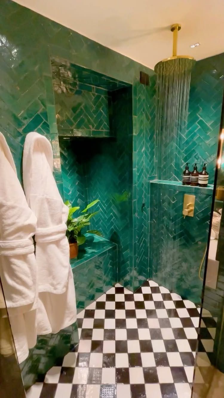 Emerald green chevron tiled shower walls with black and white checkered floor tiles.