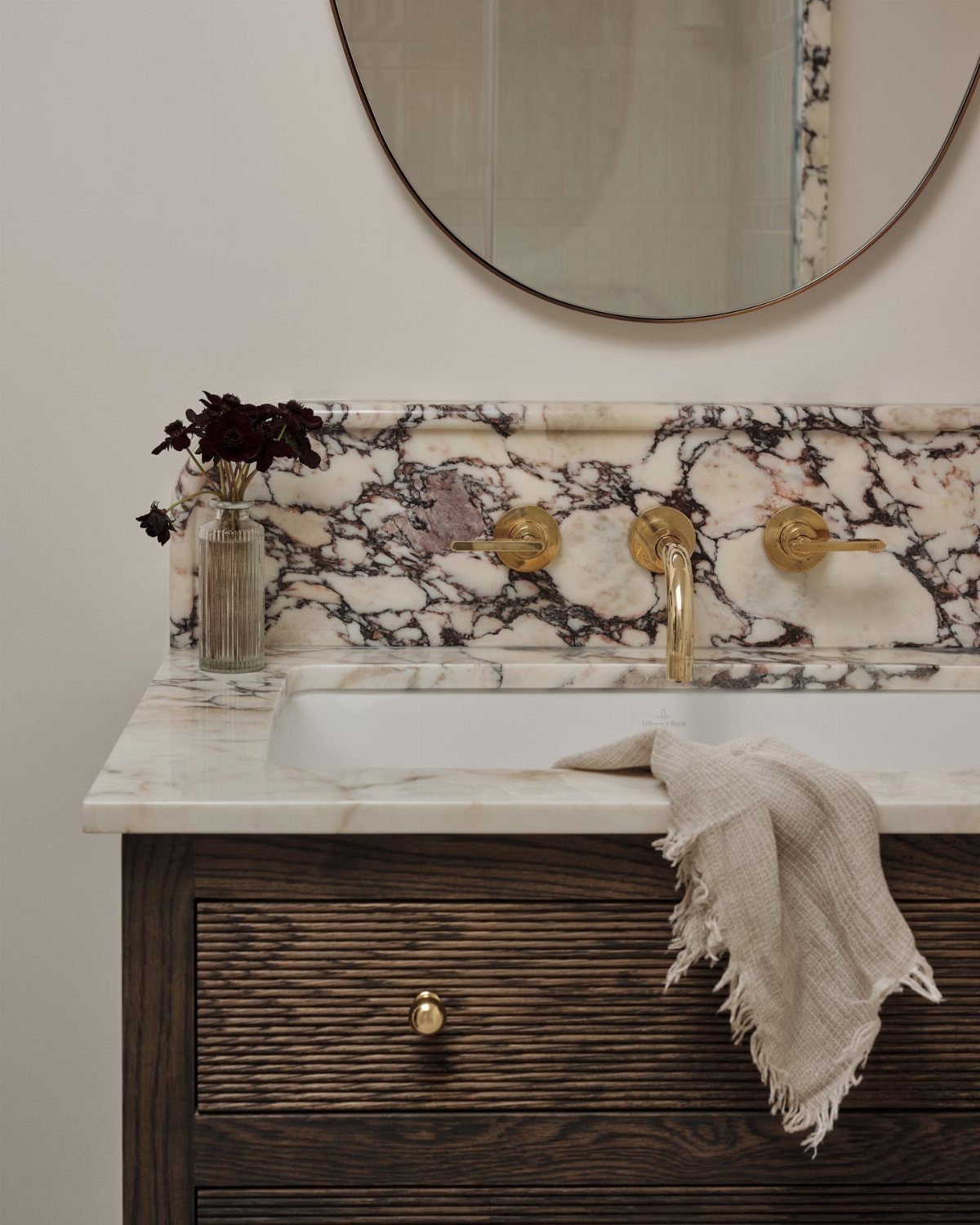 Marble tile backsplash with purple veining and gold faucets above a wooden vanity