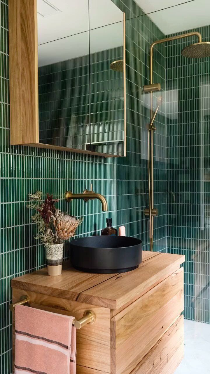 Green vertical kit-kat tile walls with a wooden vanity and gold fixtures.
