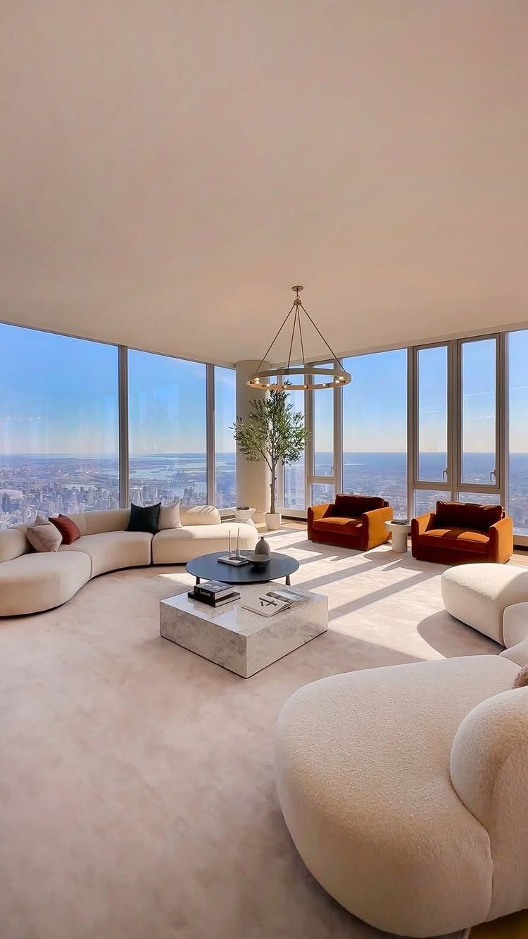 Luxury living room with curved white sofas and panoramic city skyline views.